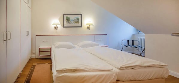 A bedroom with a bed, bedside tables, a radiator, and a picture on the wall. - Komfortplus Vacation Apartment with 1 bedroom and a balcony on the top floor (Ostseebad Binz)