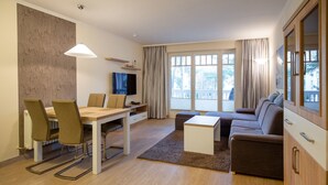 Een moderne woonkamer met een eethoek, een bank, een salontafel en een televisie.