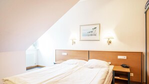 A hotel room with a large bed, a nightstand, a lamp, and a framed picture on the wall. - Classic apartment with 1 bedroom and balcony on the top floor (Ostseebad Binz)