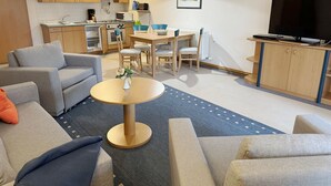 A modern living room with a sofa, a coffee table, and a TV. - Classic apartment with 1 bedroom and balcony on the top floor (Ostseebad Binz)