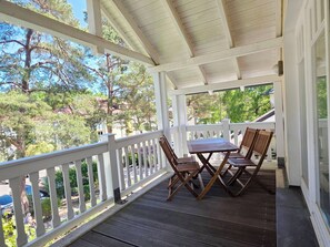 A covered porch with a white railing, a table, and two chairs. - Classic 1-Bedroom Apartment with a Balcony on the Top Floor (Ostseebad Binz)