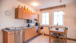 Eine moderne Küche mit Holzausbau, Edelstahlgeräten, einem Essbereich mit Tisch und Stühlen sowie einem Fenster mit Vorhängen.