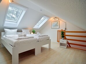 A modern bedroom with a skylight, a bed with white linens, a bedside table, and a wooden headboard. - Comfort apartment with 2 bedrooms and balcony on the top floor (Ostseebad Binz)