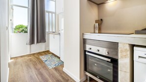 Een moderne keuken met witte kasten, een roestvrijstalen oven en een raam met uitzicht op groen.
