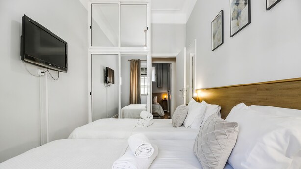Een hotelkamer met twee bedden, een flatscreen televisie aan de muur en kunstwerken op de wanden.