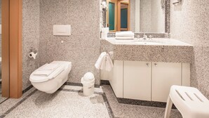 Une salle de bain comprenant des toilettes, un bidet, un lavabo et un miroir.