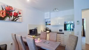 A modern kitchen with white cabinets, a microwave, and a built-in oven. - Comfort plus apartment with 2 bedrooms and balcony on the upper floor (Ostseebad Binz)