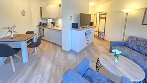 A modern apartment with a kitchen, dining area, and living room. - Komfortplus Ferienwohnung mit 1 Schlafzimmer und Balkon im Dachgeschoss (Ostseebad Binz)