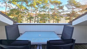 An outdoor balcony with a table and two chairs, overlooking a residential area with trees and houses. - Komfortplus Ferienwohnung mit 1 Schlafzimmer und Balkon im Dachgeschoss (Ostseebad Binz)