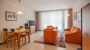 En moderne stue med spiseplads, fjernsyn og sofa.