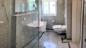 Un baño moderno con ducha envuelta en vidrio, un lavabo e inodoro.