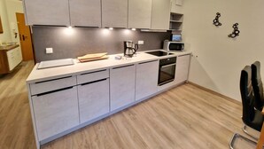 A compact kitchen with a built-in oven, microwave, and a coffee maker.