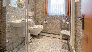 Un bagno con lavabo in marmo, un water, box doccia in vetro e porta asciugamani.