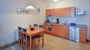 A compact kitchen with wooden cabinets, a microwave, a coffee maker, and a dishwasher. - Comfort apartment with 1 bedroom and balcony on the upper floor (Ostseebad Binz)
