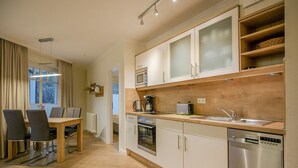 A modern kitchen with a wooden countertop, stainless steel appliances, and a dining area with a table and chairs. - Comfortplus vacation apartment with 1 bedroom and terrace on the first floor (Ostseebad Binz)