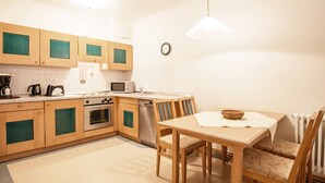 Een moderne keuken met houten kastjes, een eettafel en stoelen.