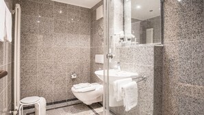 Een moderne badkamer met een douchecabine van glas, een wit toilet en een wastafel.