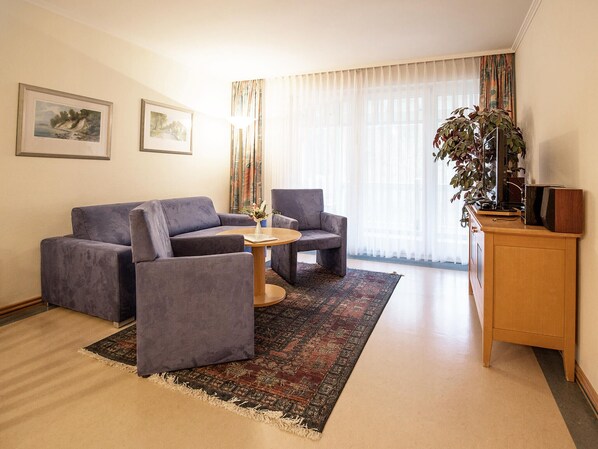 Una sala de estar moderna con un sofá, dos sillones, una mesita de centro y un mueble para la televisión.