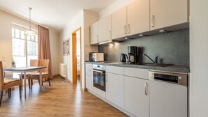 Una cocina moderna con armarios blancos, horno integrado y cafetera.