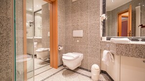 Un baño moderno con cabina de ducha de vidrio, inodoro, bidé y tocador con espejo.