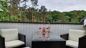 A patio with wicker chairs and a glass table, featuring a bottle and glasses. - Comfort apartment with 1 bedroom and balcony on the top floor (Ostseebad Binz)