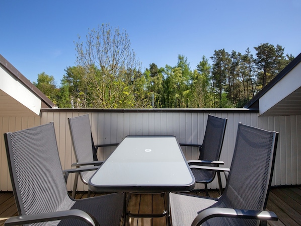 Une terrasse extérieure avec une table et quatre chaises.