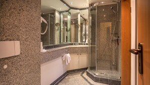 A modern bathroom with a granite countertop, a glass shower enclosure, and a wooden door. - Comfort apartment with 1 bedroom and balcony on the upper floor (Ostseebad Binz)