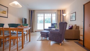 A modern living room with a dining area, a sofa, and a television. - Comfort apartment with 1 bedroom and balcony on the upper floor (Ostseebad Binz)