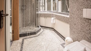 A modern bathroom with a glass-enclosed shower, a white toilet, and a granite countertop. - Comfort apartment with 1 bedroom and balcony on the upper floor (Ostseebad Binz)