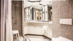 Un baño con encimera de granito, inodoro blanco y zona de ducha.