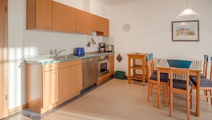 Una cocina moderna con armarios de madera, lavavajillas y un comedor con mesa y sillas.