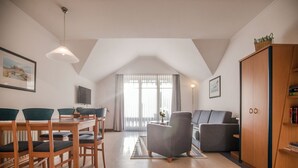 Amplia sala de estar con mesa de comedor, sillas, sofá y un mueble de madera.