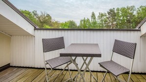 A small outdoor patio with a metal table and two chairs, surrounded by a white wall and wooden deck. - Comfort plus apartment with 1 bedroom and balcony on the top floor (Ostseebad Binz)