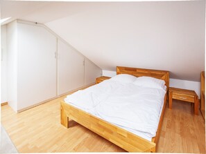 Une chambre à coucher avec un lit en bois, une table de chevet et une armoire.