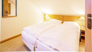 A hotel room with a bed, two bedside lamps, a mirror, and a door. - Comfort plus apartment with 1 bedroom and balcony on the top floor (Ostseebad Binz)