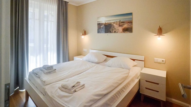 Habitación de hotel con dos camas, un cuadro en la pared y una ventana con cortinas.