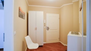 Una habitación pequeña y bien iluminada con un armario blanco, una silla blanca y una puerta.