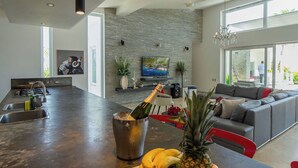Een moderne keuken met een groot eiland, een accentmuur van steen en een zithoek met een bank en een kroonluchter.