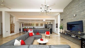 Een moderne woonkamer met een grijze modulaire bank, een salontafel en een televisie aan een stenen muur.