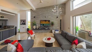 Een moderne woonkamer met een open haard, een zithoek, een salontafel, en een keuken in de achtergrond.