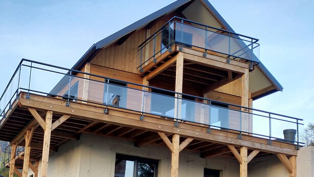 Een houten gebouw met meerdere verdiepingen en een balkon op de bovenste etage.