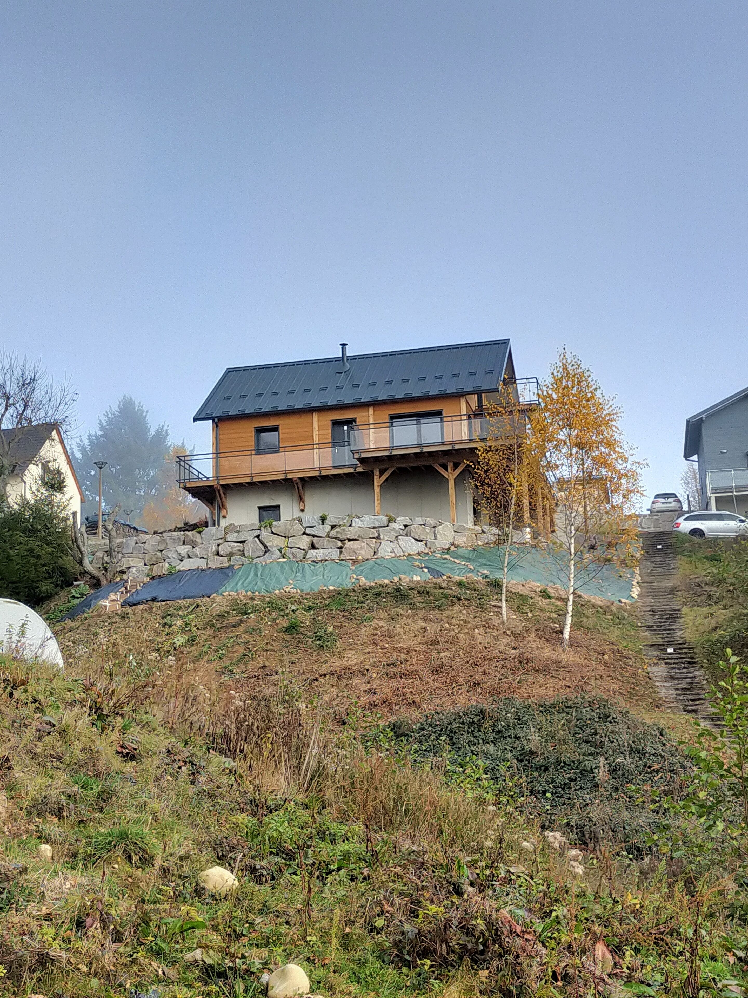 A two-story house with a stone foundation and a wooden upper level.