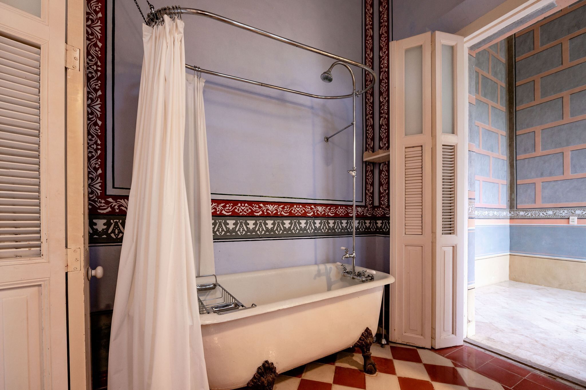 A bathroom with a clawfoot bathtub, a shower with a curtain, and a patterned wall.