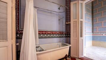 A bathroom with a clawfoot bathtub, a shower with a curtain, and a patterned wall.