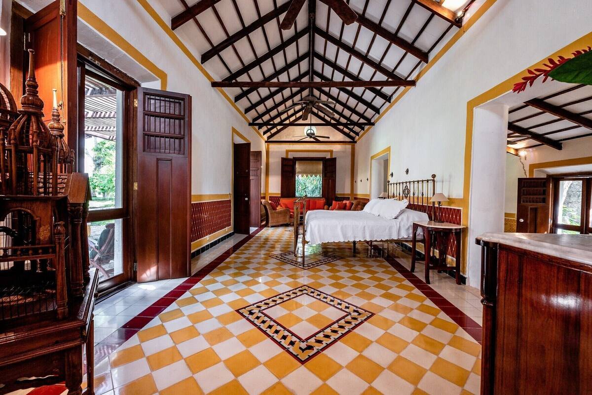 A hotel room with a checkered floor, a bed, a desk, and a window.