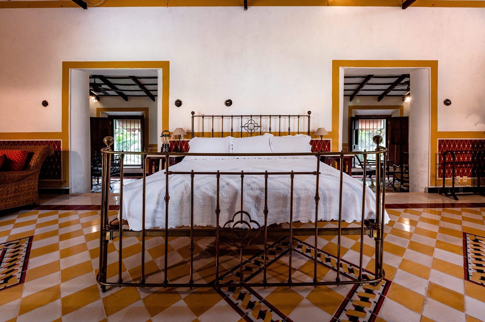 A room with a bed, checkered floor, and two doors leading to other rooms.