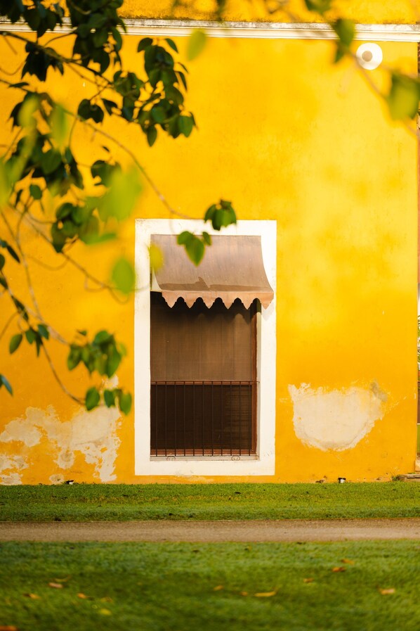 A yellow building with a small window and a white awning. - Hacienda San Antonio Millet (Tixkokob)