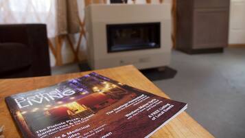 Une brochure intitulée « Beth Living » est posée sur une table en bois dans une pièce dotée d’une cheminée, d’un mur à motifs et d’une armoire.