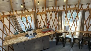 Une cuisine compacte dotée d’un plan de travail en bois, de placards intégrés et d’un coin repas avec des tabourets.