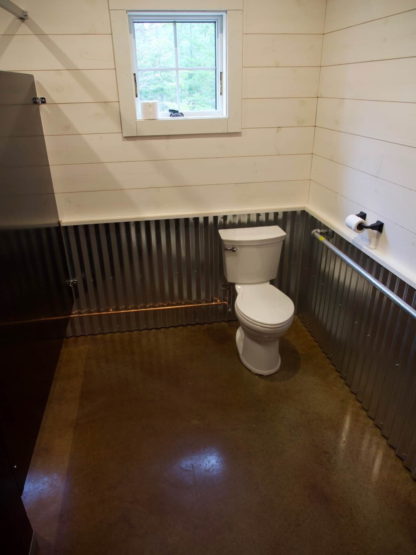 A small bathroom with a toilet, a window, and a metal radiator.